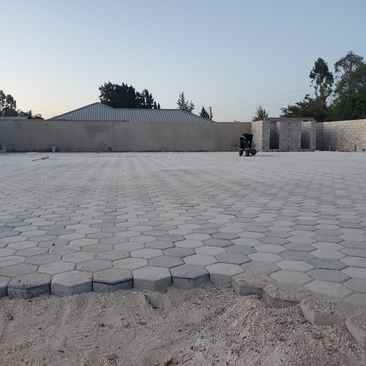 Large paved yard with boundary wall and gatehouse under construction
